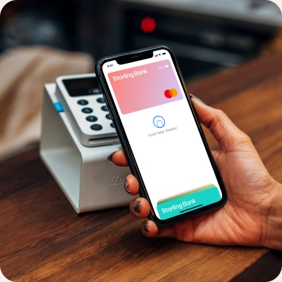 A woman is holding an iPhone in her hand, and an Apple Pay pink-coloured virtual card is opened and ready for use.