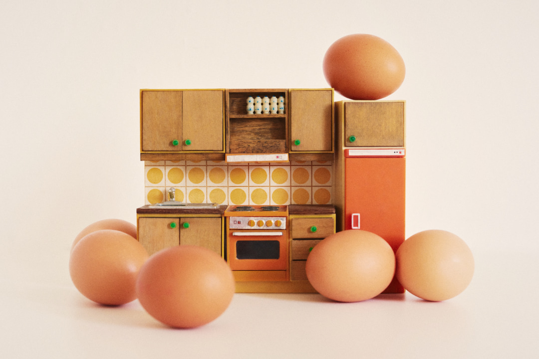 Creative photograph of a toy kitchen set surrounded by chicken eggs