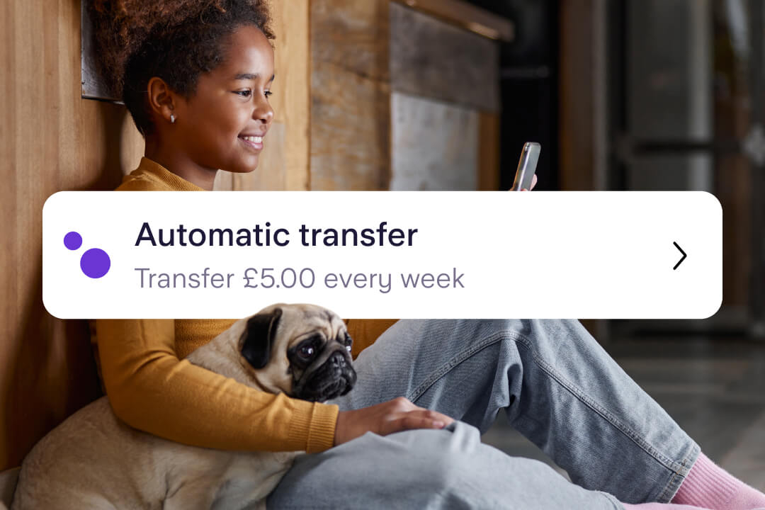 Young girl looks at her phone with a pug sitting next to her. The image is overlaid with a banner for an Automatic transfer of £5 per week onto her Kite debit card.
