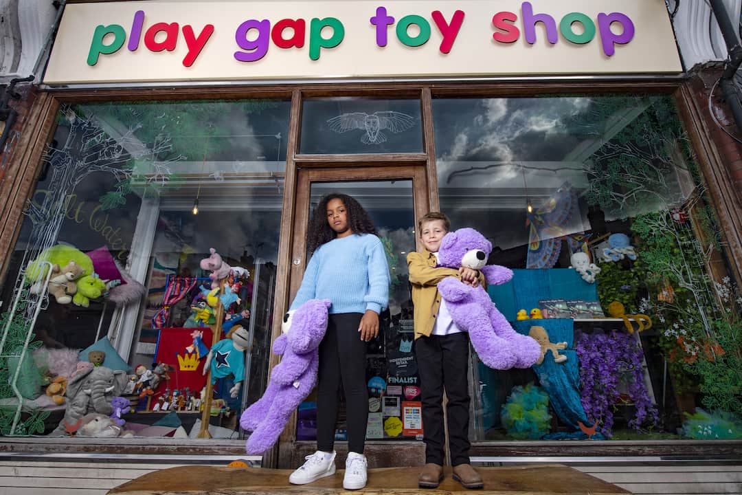 Kids in front of a toy shop holding bears