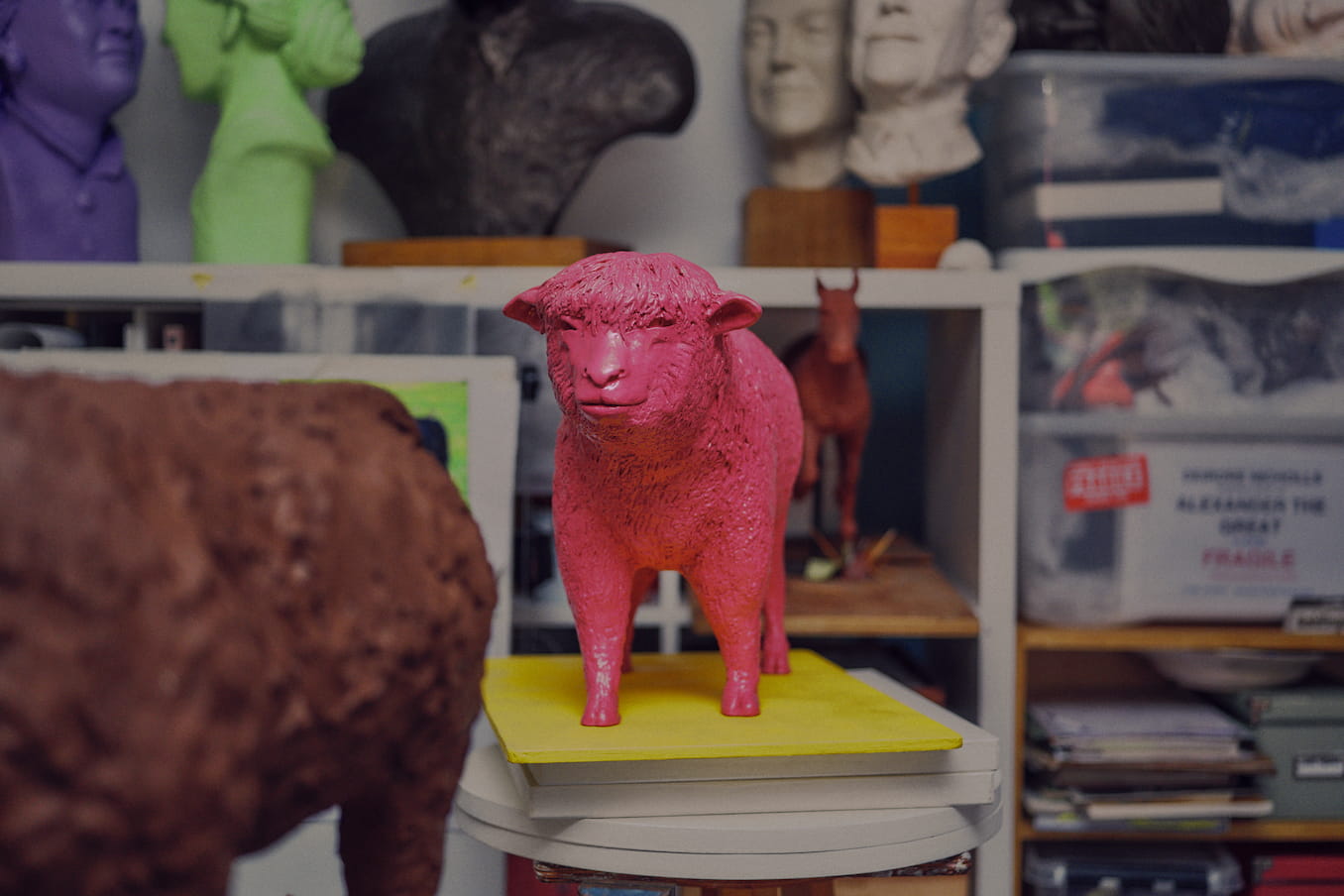 Pink sculpture of a sheep, titled Hello Dolly, standing on a yellow plinth in Deirdre Nicholl's studio