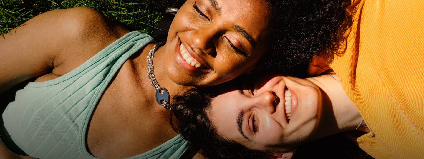 2 people laying in the grass in the sun