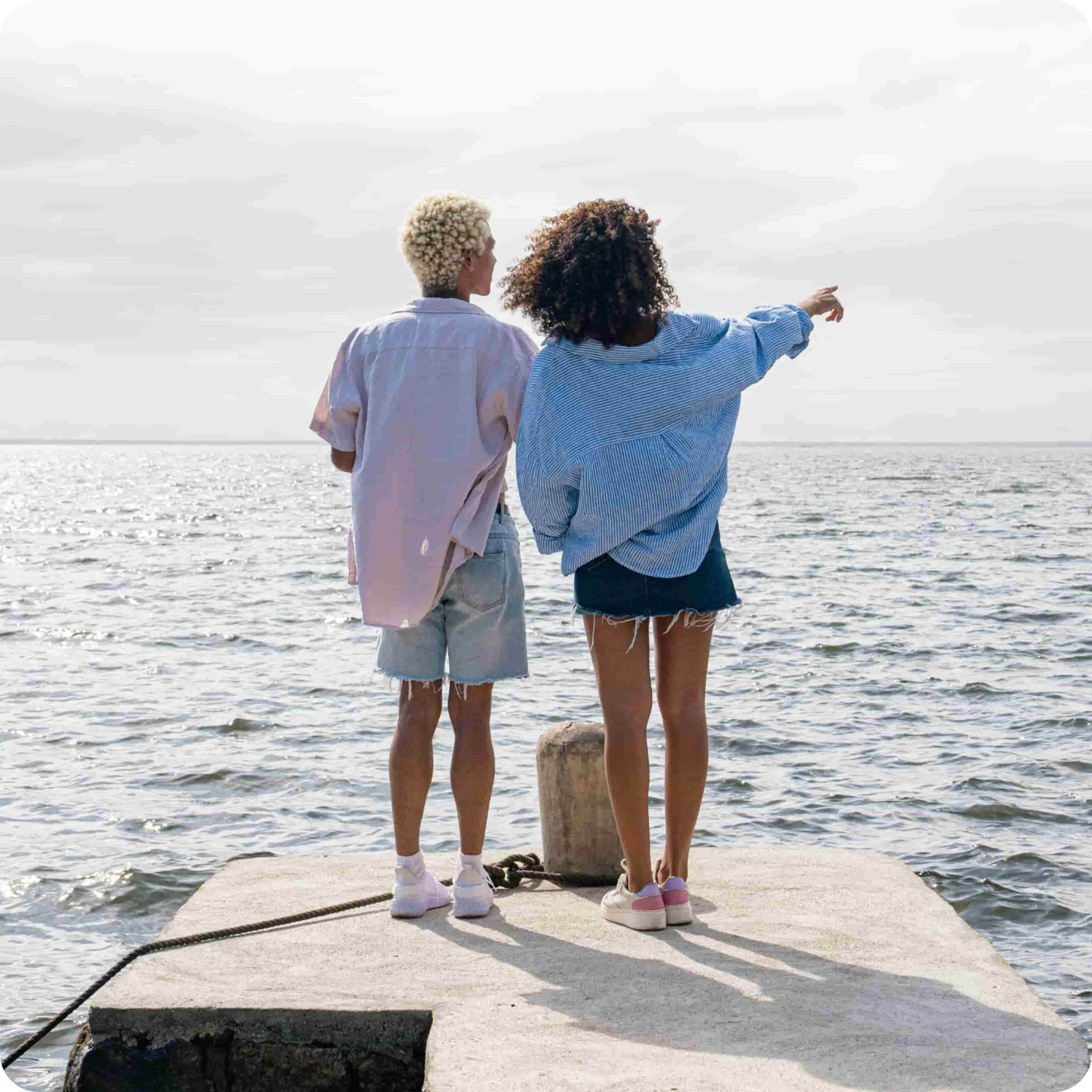 An image showing the back of two people looking out to the sea horizon