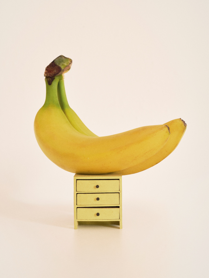 Creative photograph of two bananas on top of a doll's house sized chest of drawers