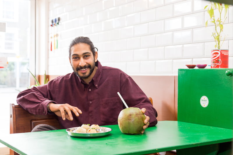 Nish smiles with a drink and food