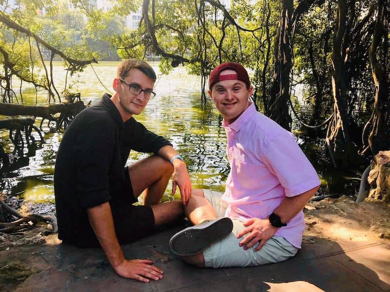 Nick and Alex smile sitting by water