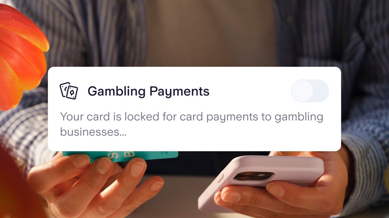 The gambling block setting shown over the top of a person holding a phone and a Starling card